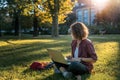 Young businesswoman student working on her notebook in park. Freelancer female sitting on grassy lawn using laptop computer with Royalty Free Stock Photo