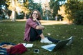 Young businesswoman student working on her notebook in park. Freelancer female sitting on grassy lawn using laptop computer with Royalty Free Stock Photo