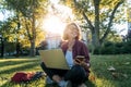 Young businesswoman student working on her notebook in park. Freelancer female sitting on grassy lawn using laptop computer with Royalty Free Stock Photo