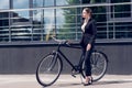 young businesswoman in suit and high heels standing near retro bicycle