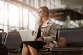 Young businesswoman in sunglasses with luggage in airport waiting room working laptop Royalty Free Stock Photo
