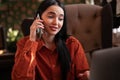 Young businesswoman talking on her phone and using a laptop during work day at cafe. Royalty Free Stock Photo