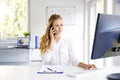 Young businesswoman talking with somebody on her mobile phone while sitting at office desk Royalty Free Stock Photo