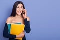 Young businesswoman talking via phone with happy facial expression, wearing stylish dress with bare shoulders, holding colored Royalty Free Stock Photo
