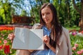 Young businesswoman teacher holding opened notebook with empty pages in spring park. Copy space. Mockup Royalty Free Stock Photo