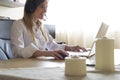 Young businesswoman teleworking sitting at a desk talking with clients with hear headphones on and typing on her laptop in a home Royalty Free Stock Photo