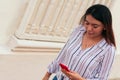 Young businesswoman typing on cell phone while walking on a city pathway