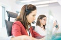 Young businesswoman using headset with female colleague in background at office Royalty Free Stock Photo