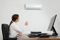 Businesswoman Using Remote Control In Front Of Air Conditioner Royalty Free Stock Photo