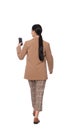 Young businesswoman using smartphone while walking on white background, back view Royalty Free Stock Photo