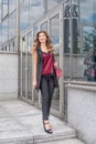 Young businesswoman walks out of the office with a red handbag