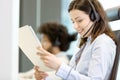 Young businesswoman wearing headset while reading document in office Royalty Free Stock Photo