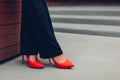 Young businesswoman wearing red high heeled shoes. Stylish classic pumps. Closeup of female legs.