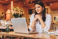 Businesswoman sitting in cafe at table,looking on screen of computer, smiling. Distance work. Online marketing,education Royalty Free Stock Photo