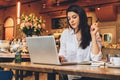 Businesswoman sitting in cafe at table,looking on screen of computer, smiling. Distance work. Online marketing,education Royalty Free Stock Photo