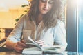 Young businesswoman in white shirt sitting at table and reading book. Girl leafing through book Royalty Free Stock Photo