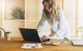 Young businesswoman woman is standing near kitchen table,uses laptop,working, studying.On table tablet computer Royalty Free Stock Photo