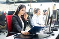 Young businesswoman working with a headset and accompanied by her team in call center. Royalty Free Stock Photo