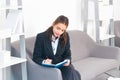 Young businesswoman working on laptop with too much work in office. Secretary girl making notes in note book. Royalty Free Stock Photo