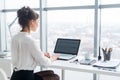 Young businesswoman working in office, typing, using computer. Concentrated woman searching information online, rear