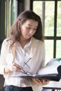 Young businesswoman at workplace and reading paper in office. business woman wearing suit holding documents in hand Royalty Free Stock Photo