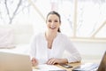 Young businesswoman writing something while sitting at office de