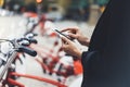 Young businesswomen in black suit and umbrella using smartphone, biking and going to work by city bicycle on urban street Royalty Free Stock Photo