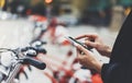 Young businesswomen in black suit and umbrella using smartphone, biking and going to work by city bicycle on urban street Royalty Free Stock Photo