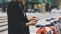 Young businesswomen in black  suit and umbrella using smartphone, biking and going to work by city bicycle on urban street Royalty Free Stock Photo