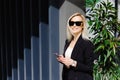 Young businesswomen in black suit using smartphone isolated on background gray wall. Pretty manager holding mobile gadget and Royalty Free Stock Photo