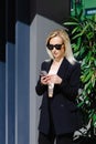 Young businesswomen in black suit using smartphone isolated on background gray wall. Pretty manager holding mobile gadget and Royalty Free Stock Photo