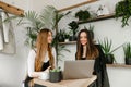 Young businesswomen in casual clothes at a meeting in cafe, communicate with a smile on their faces and enjoy a laptop. Two Royalty Free Stock Photo