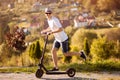 Young bussinesman with electric scooter rushes to work by park