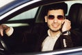 Young bussinesman in suit and black glasses speaks by phone in his car. Bussines look. Test drive of the new car Royalty Free Stock Photo