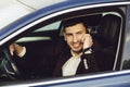 Young bussinesman in suit speaks by phone in his car. Bussines look. Test drive of the new car Royalty Free Stock Photo