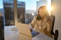 Young busy Asian business woman working using phone laptop in sunny office. Royalty Free Stock Photo