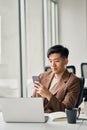 Young busy smiling Asian business man using mobile phone in office. Royalty Free Stock Photo