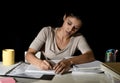 Young busy beautiful Spanish girl studying at home late night looking preparing exam writing on notepad Royalty Free Stock Photo