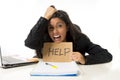 Young busy desperate Latin businesswoman holding help sign sitting at office desk in stress worried