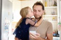 Young busy father with his little curly hair daughter together at home. Preschooler girl hugging and kissing her daddy