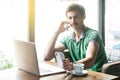 Young busy multiple businessman in green t-shirt sitting and working on laptop. talking on phone and looking at another smartphone