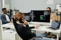 Young busy programmer talking on mobile phone while sitting in front of computer