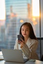 Young busy serious Asian business woman using phone in corporate office. Royalty Free Stock Photo