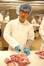 A young butcher cutting meat Royalty Free Stock Photo