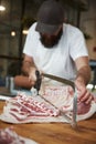 Young butcher sawing meat at a butcher's shop, vertical