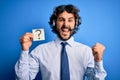 Young call center agent man with beard working using headset holding question mark reminder screaming proud and celebrating Royalty Free Stock Photo