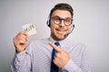 Young call center operator business man with blue eyes offering support holding paper note very happy pointing with hand and Royalty Free Stock Photo