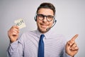 Young call center operator business man with blue eyes offering support holding paper note very happy pointing with hand and Royalty Free Stock Photo