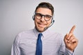 Young call center operator business man with blue eyes wearing glasses and headset with a big smile on face, pointing with hand Royalty Free Stock Photo