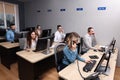 Young call center operator talking on phone and her colleagues working in modern office Royalty Free Stock Photo